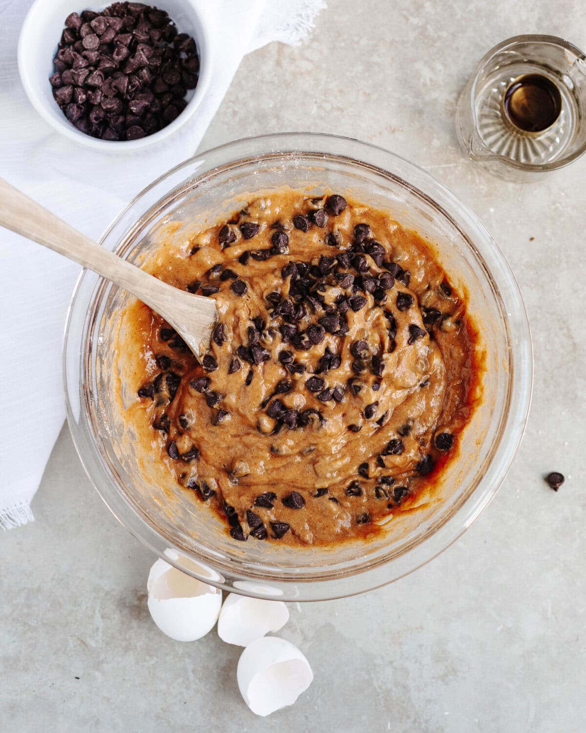 Chocolate chips folded into a muffin batter in a glass mixing bowl.