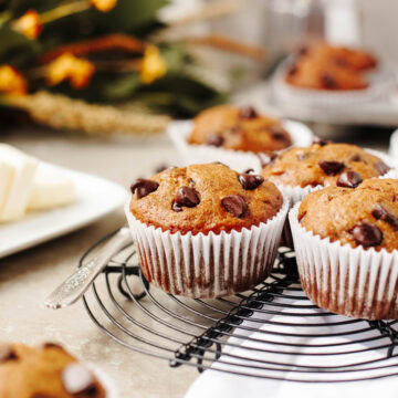 An up close look at baked pumpkin banana chocolate chip muffins on a black wire rack.