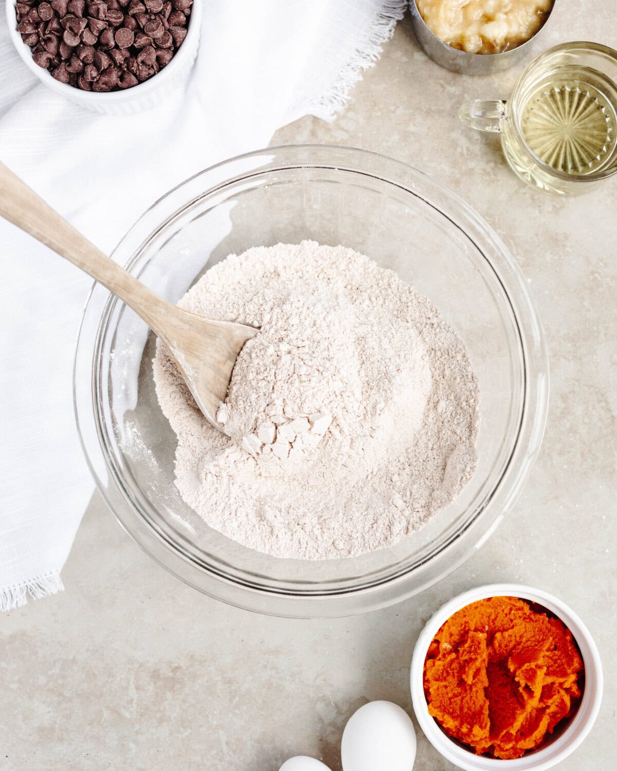 Flour, baking powder, baking soda, salt, ground cinnamon, and sugar combined in a glass bowl.