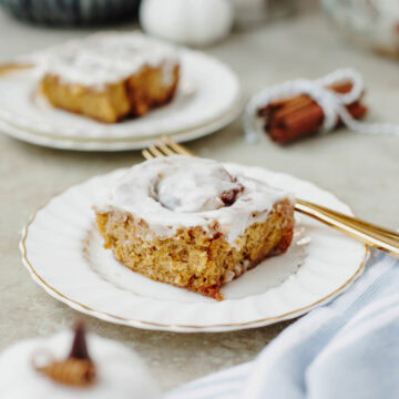 A pumpkin cinnamon roll served on a white plate.