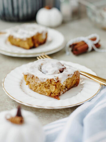 A pumpkin cinnamon roll served on a white plate.