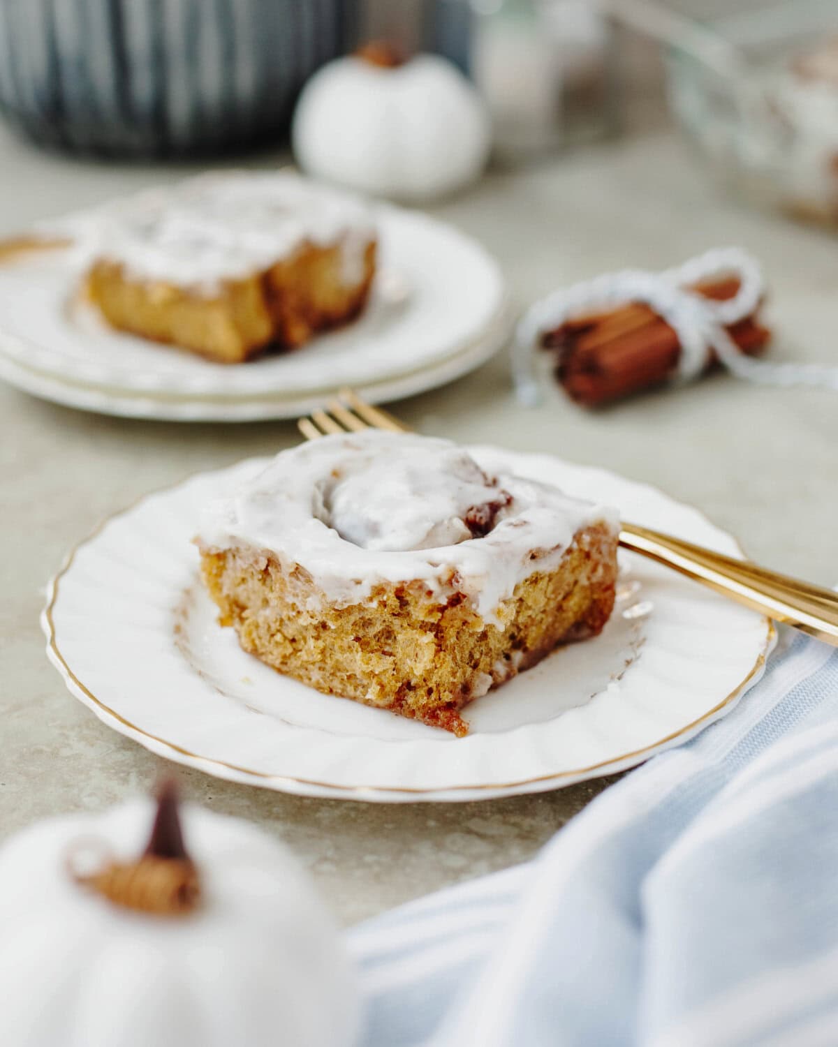 A pumpkin cinnamon roll served on a white plate.