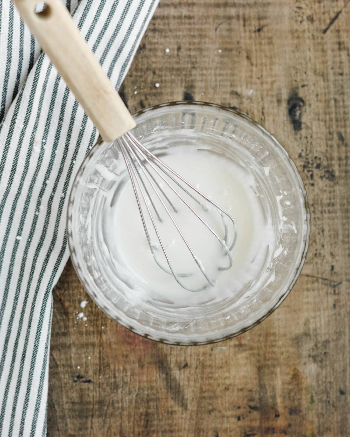 A powdered sugar glaze whisked together in a glass mixing bowl.