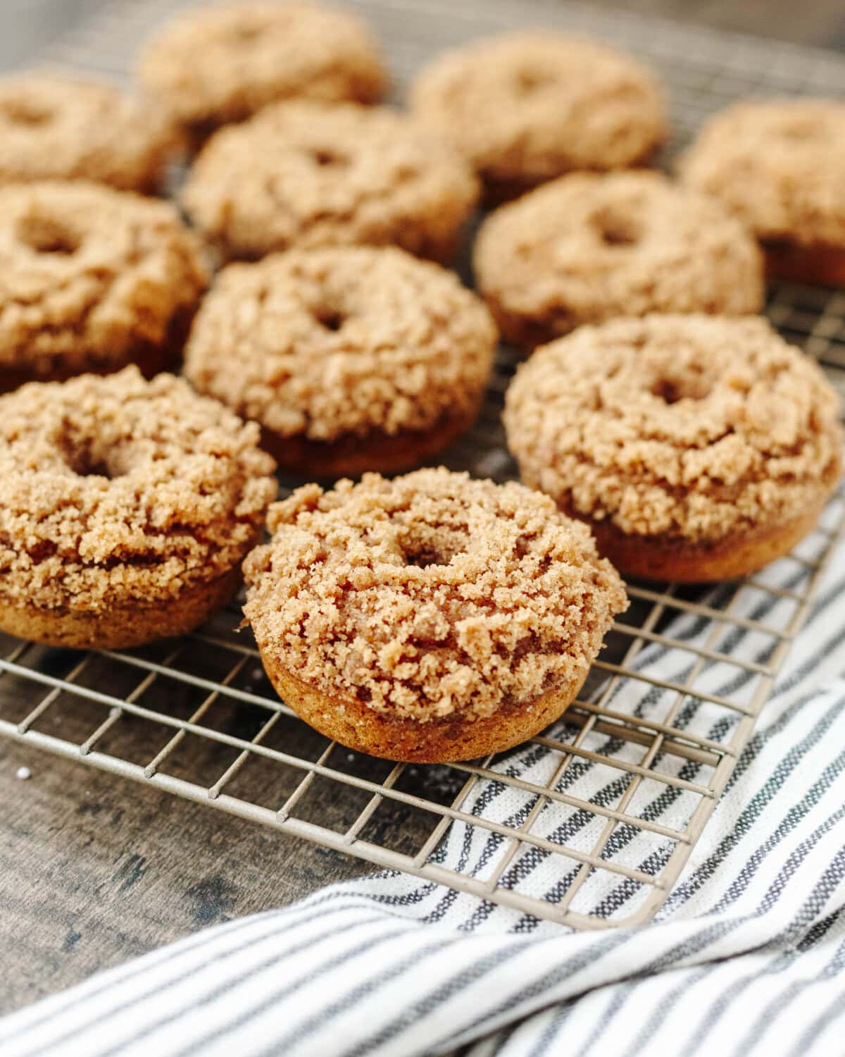 A wire rack with baked donuts cooling from the oven.