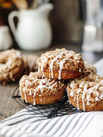 A stack of pumpkin coffee cake donuts on a wire rack.