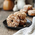 Pumpkin coffee cake donuts stacked on a black serving plate.