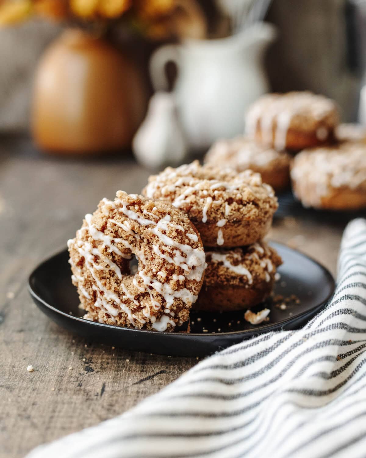 Pumpkin coffee cake donuts stacked on a black serving plate.
