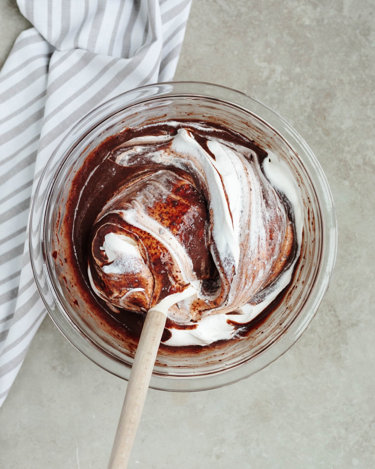 Whipped topping folded into a boozy chocolate mixture in a glass mixing bowl.