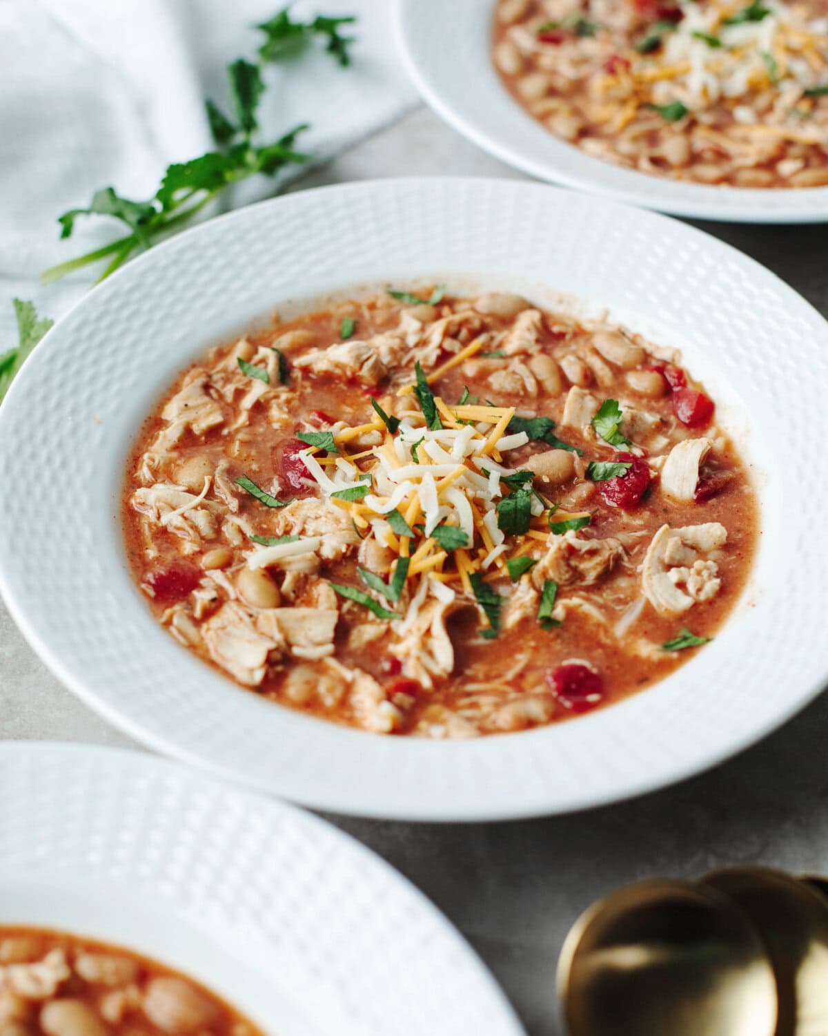 Slow Cooker Taco Ranch Chili with shredded cheese, cilantro, and tortilla chips.