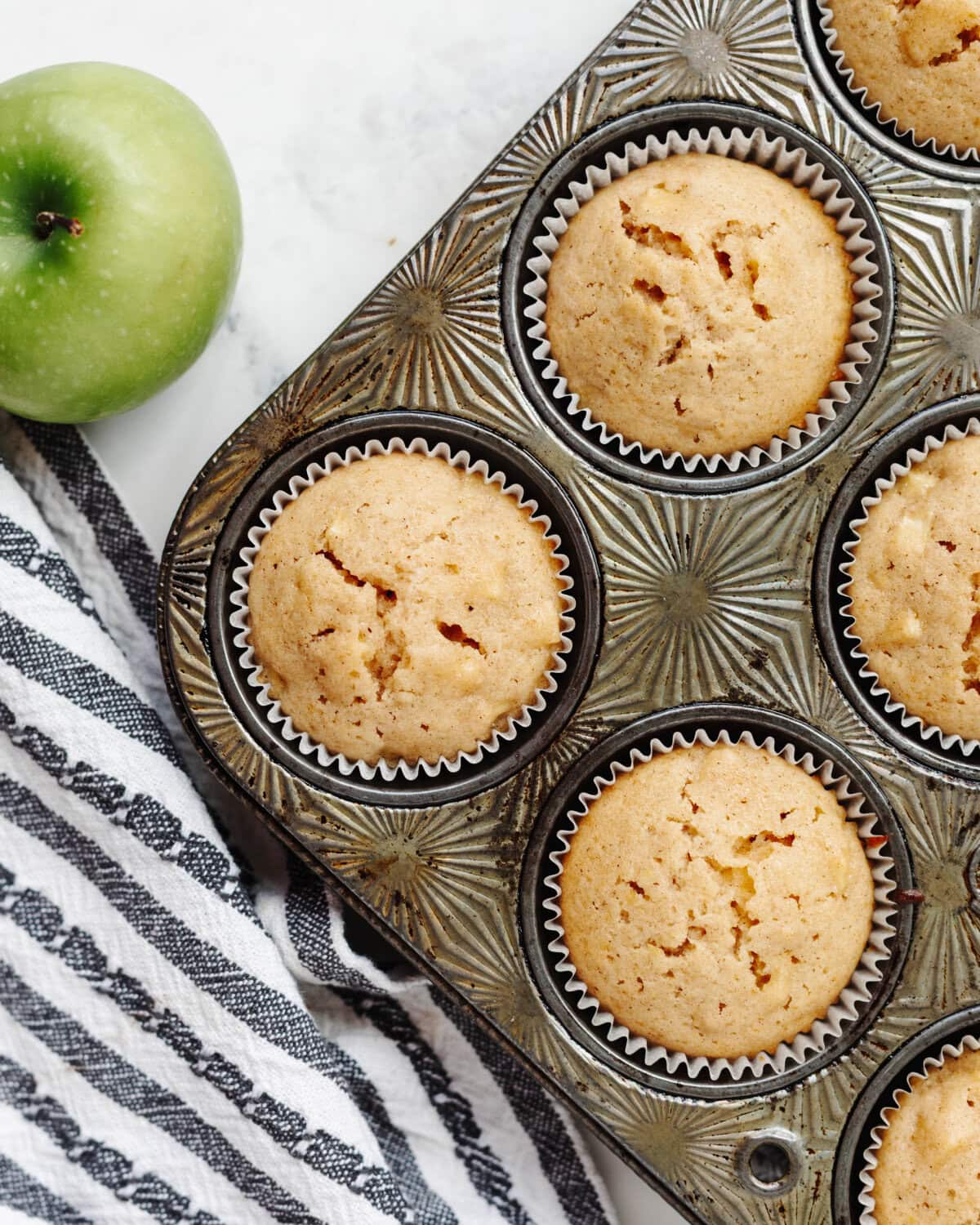 Baked apple muffins in a muffin pan.