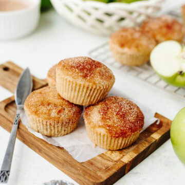 Stacked snickerdoodle apple muffins on a wood cutting board.