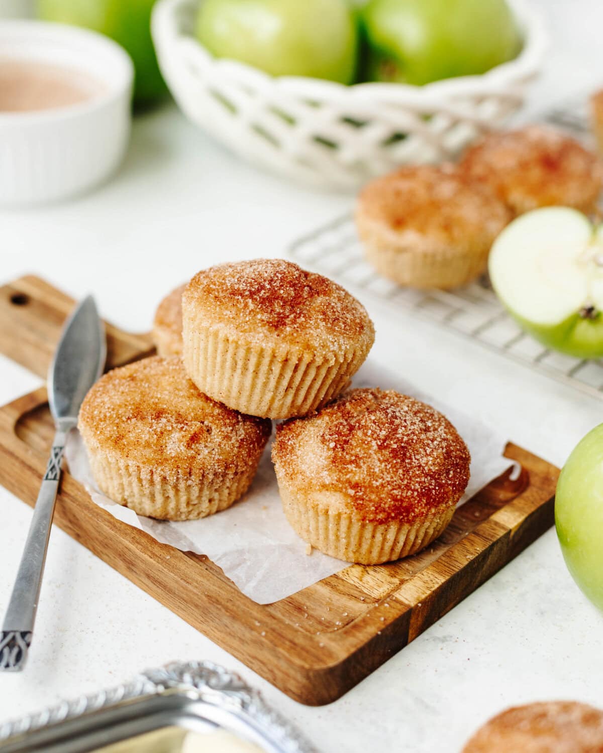 Stacked snickerdoodle apple muffins on a wood cutting board.