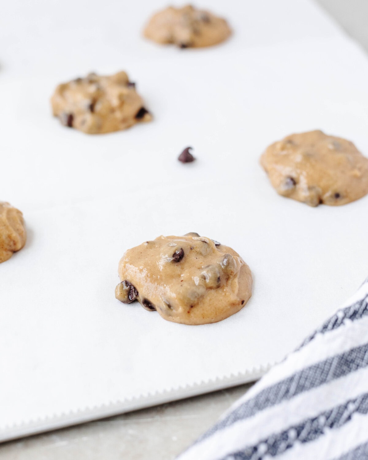 Cookie dough batter dropped onto a parchment lined cookie sheet.