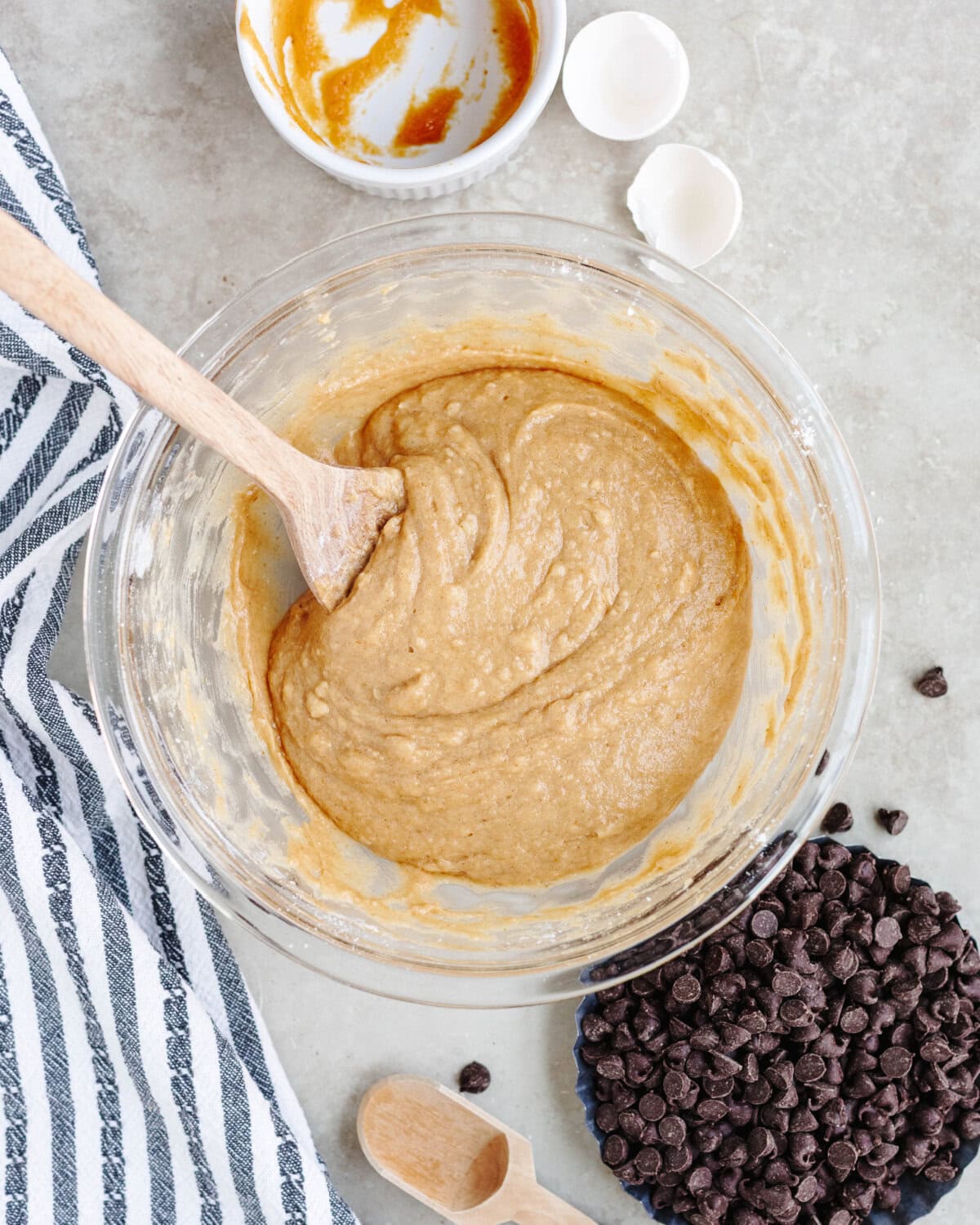 Pumpkin, sugar, vanilla, milk, oil, egg, flour, baking powder, soda, salt, and cinnamon combined in a glass mixing bowl.
