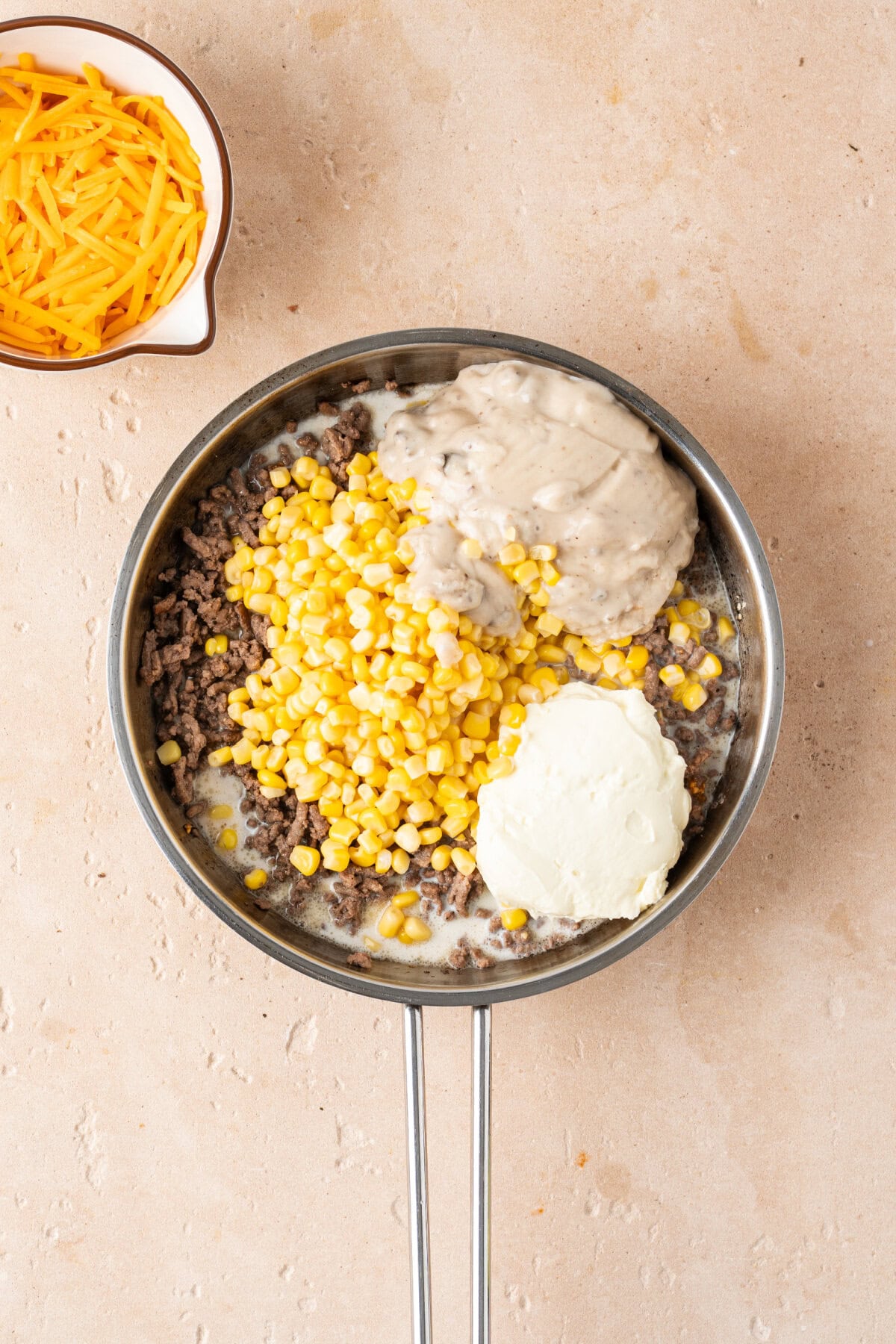 Corn, sour cream, cream of mushroom, milk, and ground beef combined in a skillet.