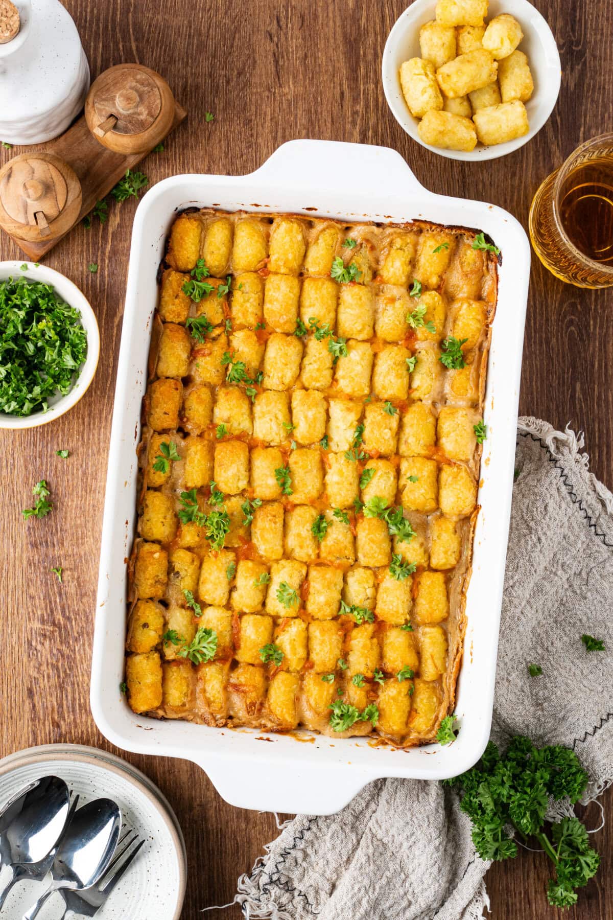Baked tater tot casserole in a white ceramic baking dish from the oven.