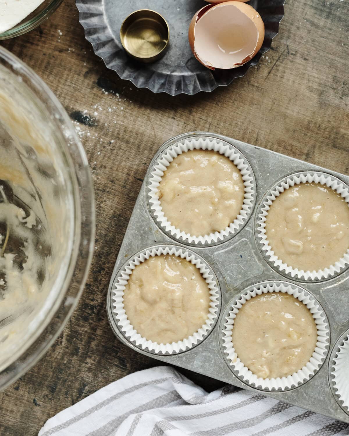 Muffin batter poured evenly into white paper liners.