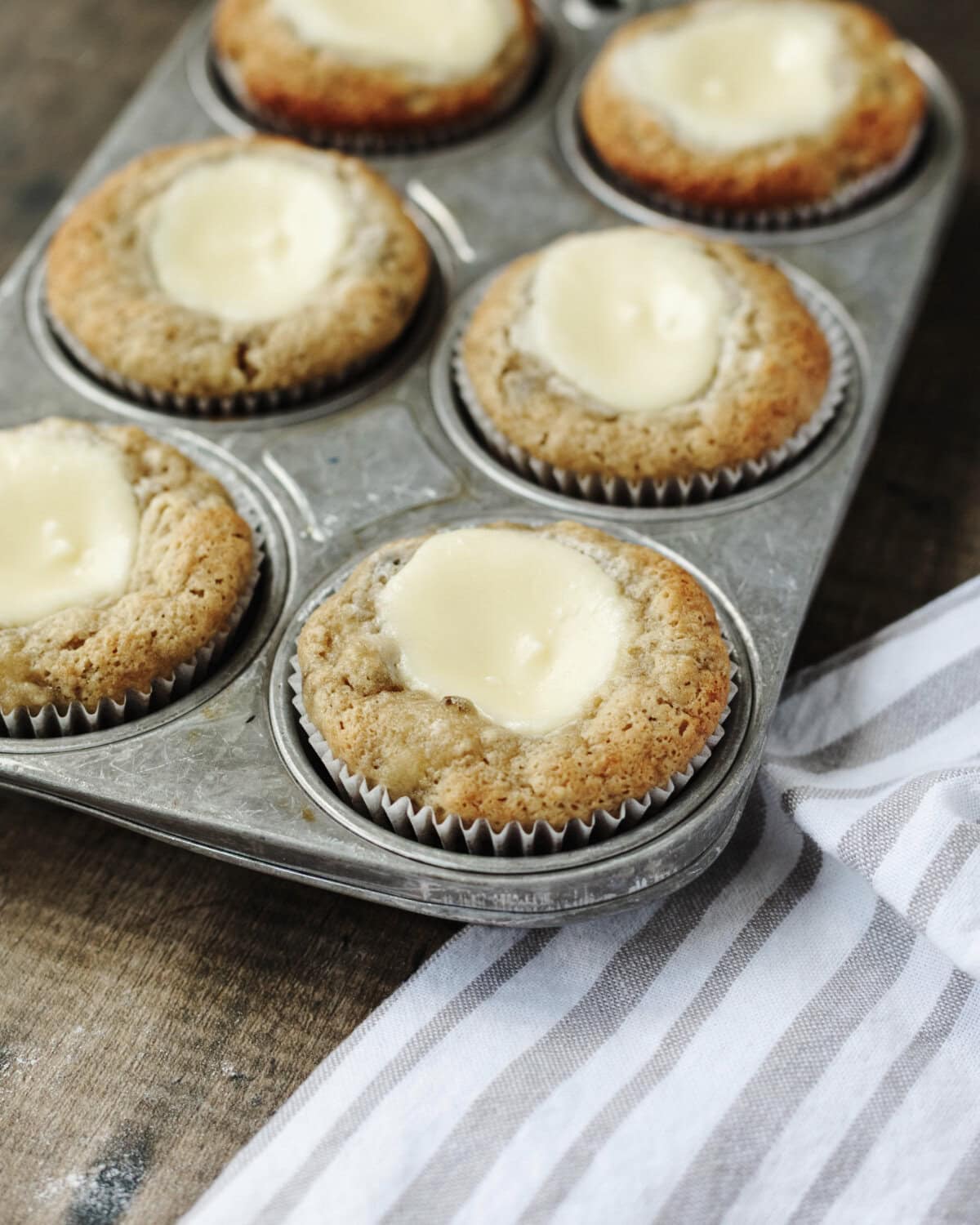 Baked banana cream cheese muffins in a muffin pan.