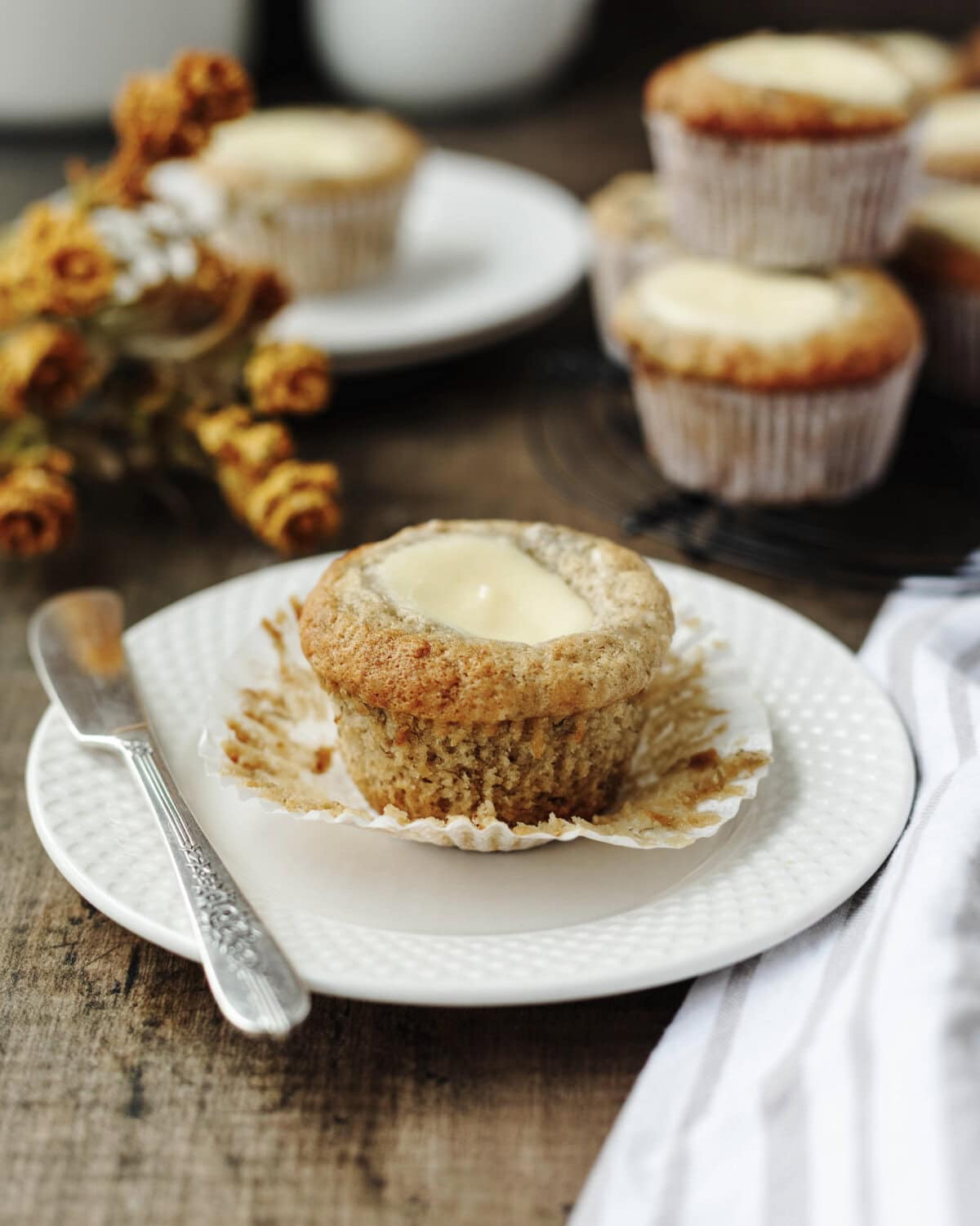 A banana muffin with cream cheese filling on a small white plate.