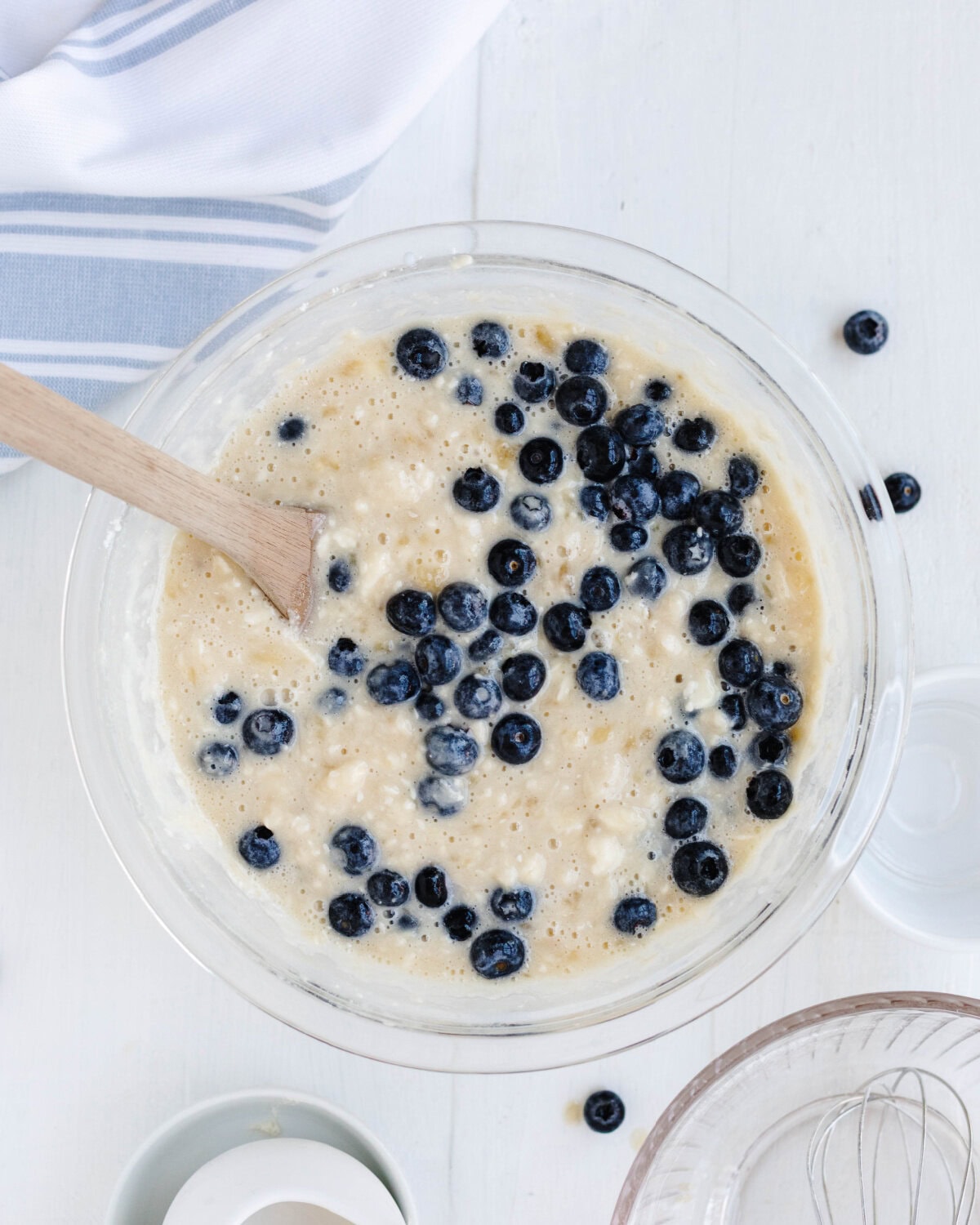 Blueberries folded into a banana mixture in a glass bowl.