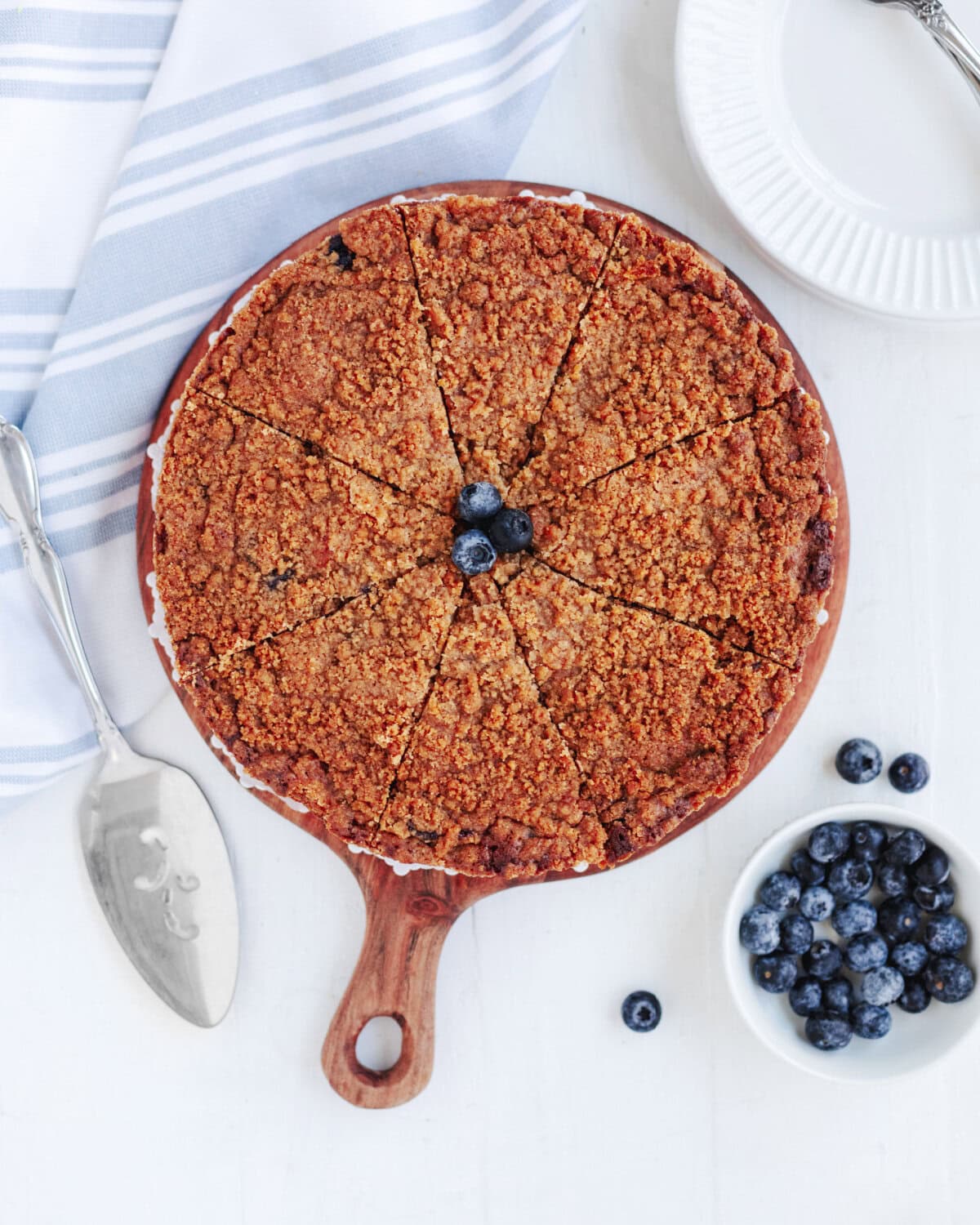 A baked blueberry banana crumb cake on a wood serving board.