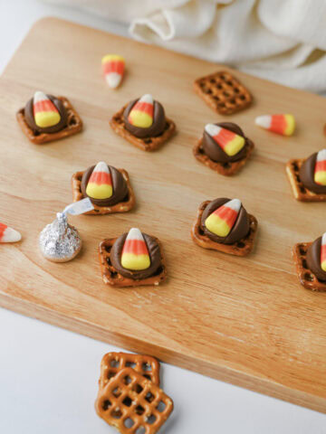 Candy corn pretzel hugs on a wood cutting board ready to serve.