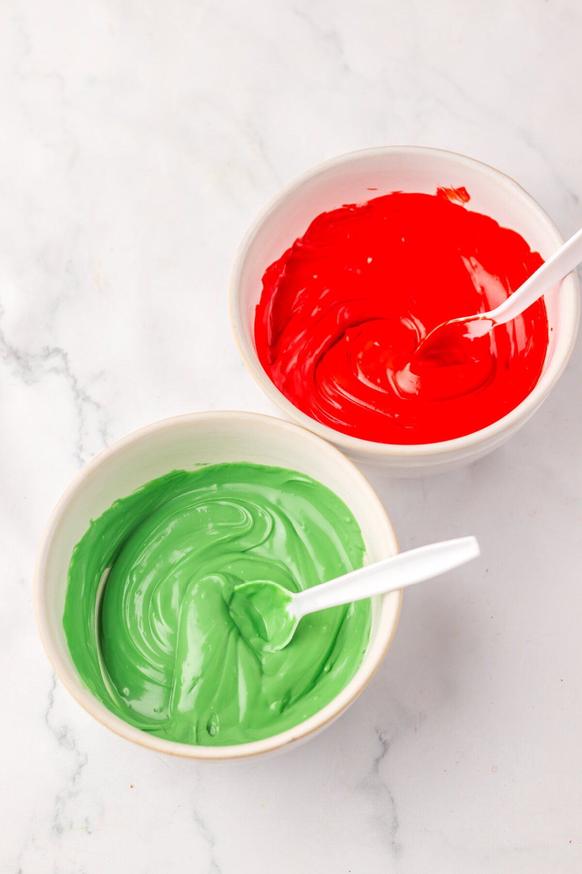 Red and green candy melts melted in small white bowls.