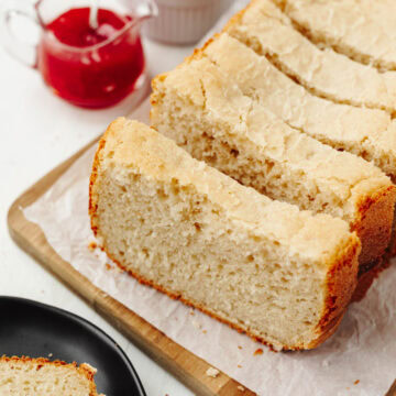Sliced loaf of country white bread on a wood cutting board.