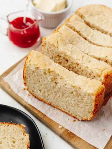 Sliced loaf of country white bread on a wood cutting board.