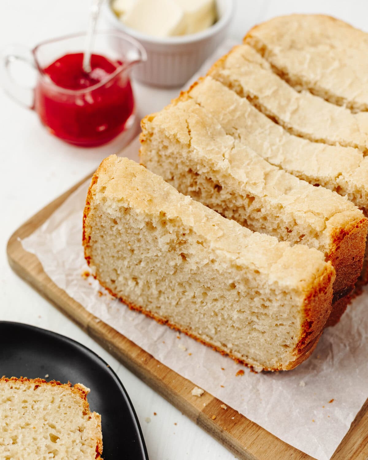 Sliced loaf of country white bread on a wood cutting board.