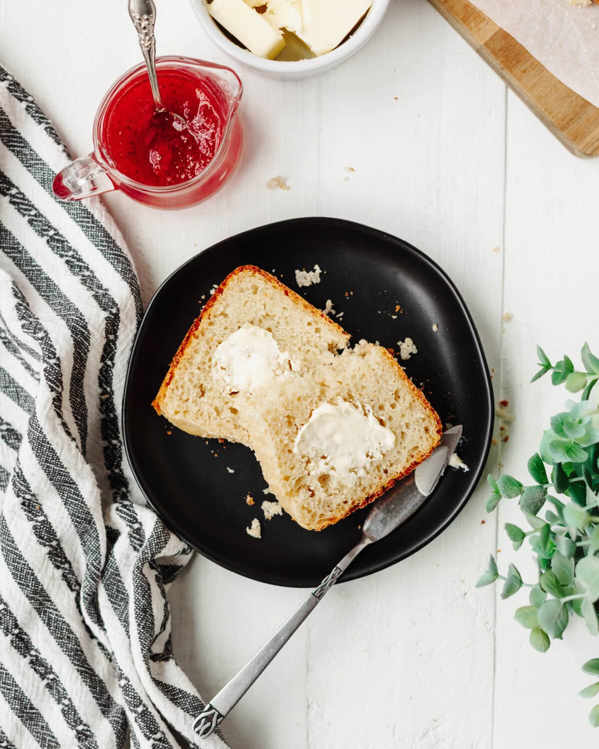 Sliced country white bread on a black serving plate with butter.
