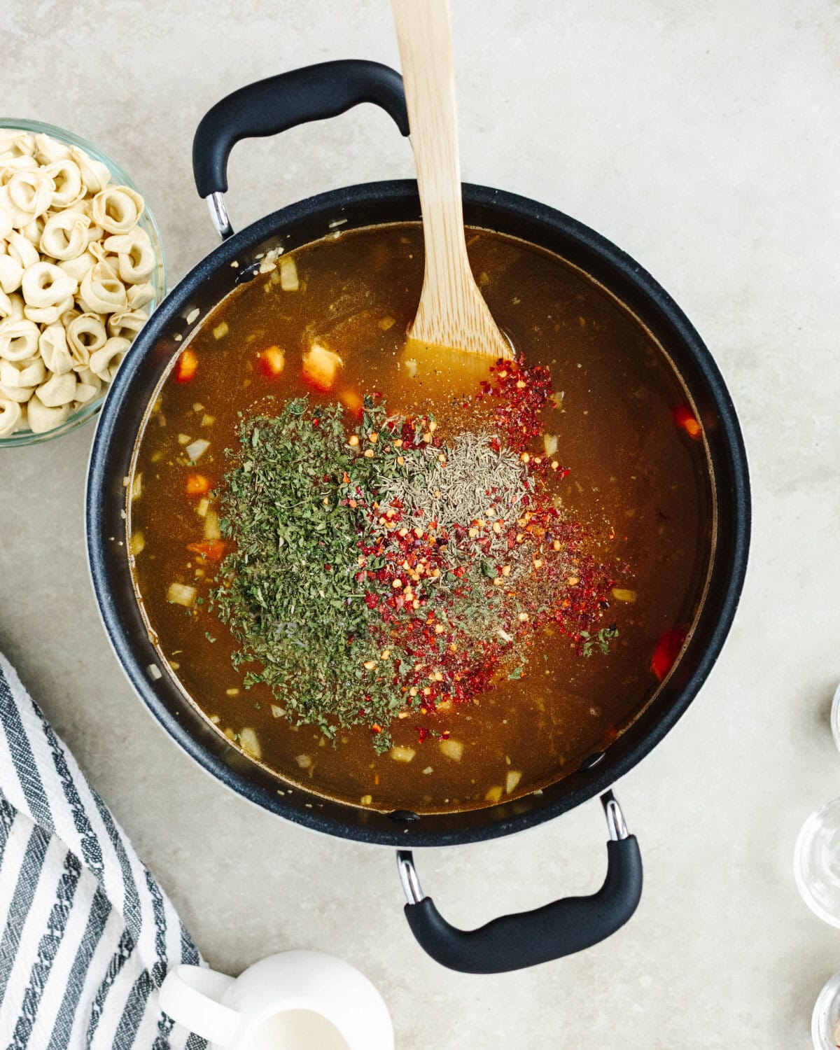 Raw chicken breasts, chicken broth, dried thyme, crushed red pepper, salt, and ground black pepper added to a pot to simmer.