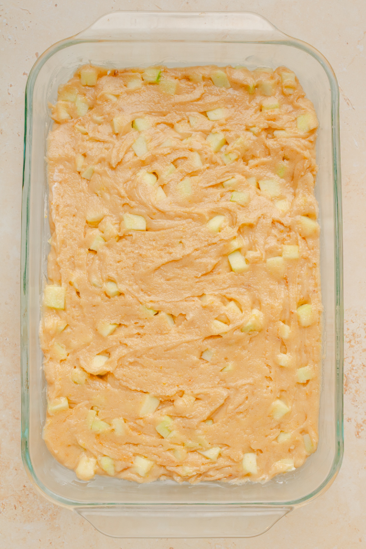 Cake batter spread evenly into a prepared 9x13 glass baking pan.