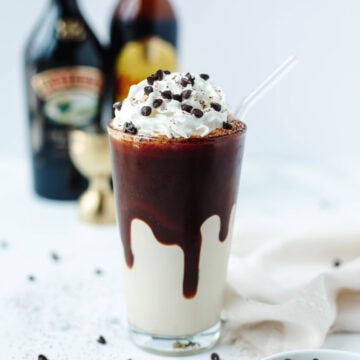 A frozen mudslide in a glass garnished with whipped cream and chocolate syrup.
