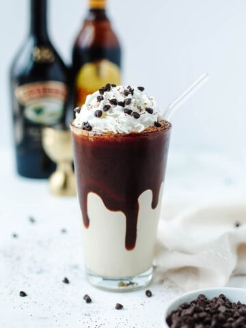 A frozen mudslide in a glass garnished with whipped cream and chocolate syrup.