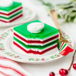 A piece of layered Jello served on a floral plate with a fork.