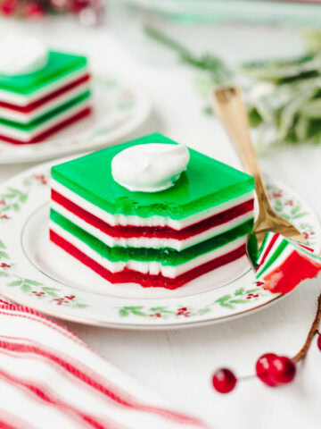 A piece of layered Jello served on a floral plate with a fork.