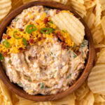 A brown bowl with million dollar dip served with chips.