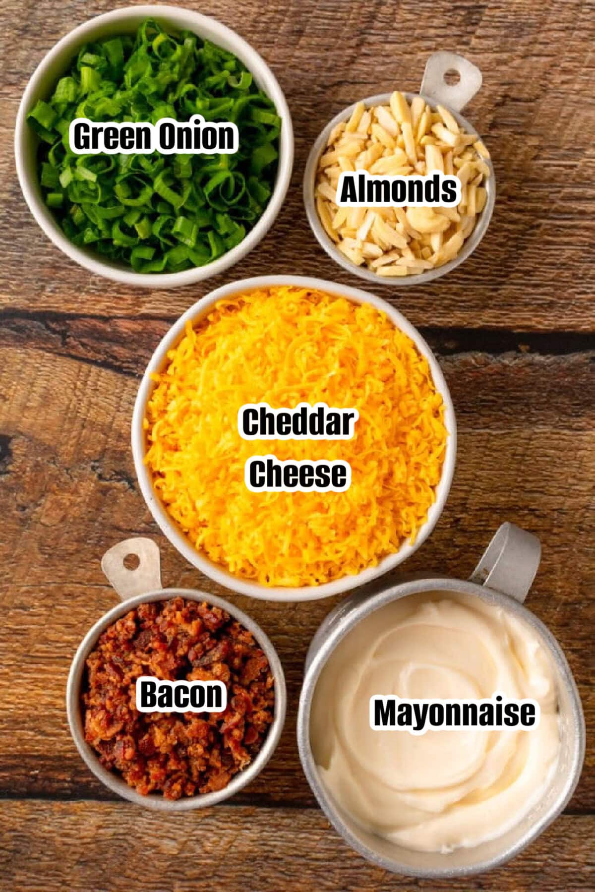 Green onions, cheddar cheese, almonds, bacon, and mayonnaise in bowls to make dip.