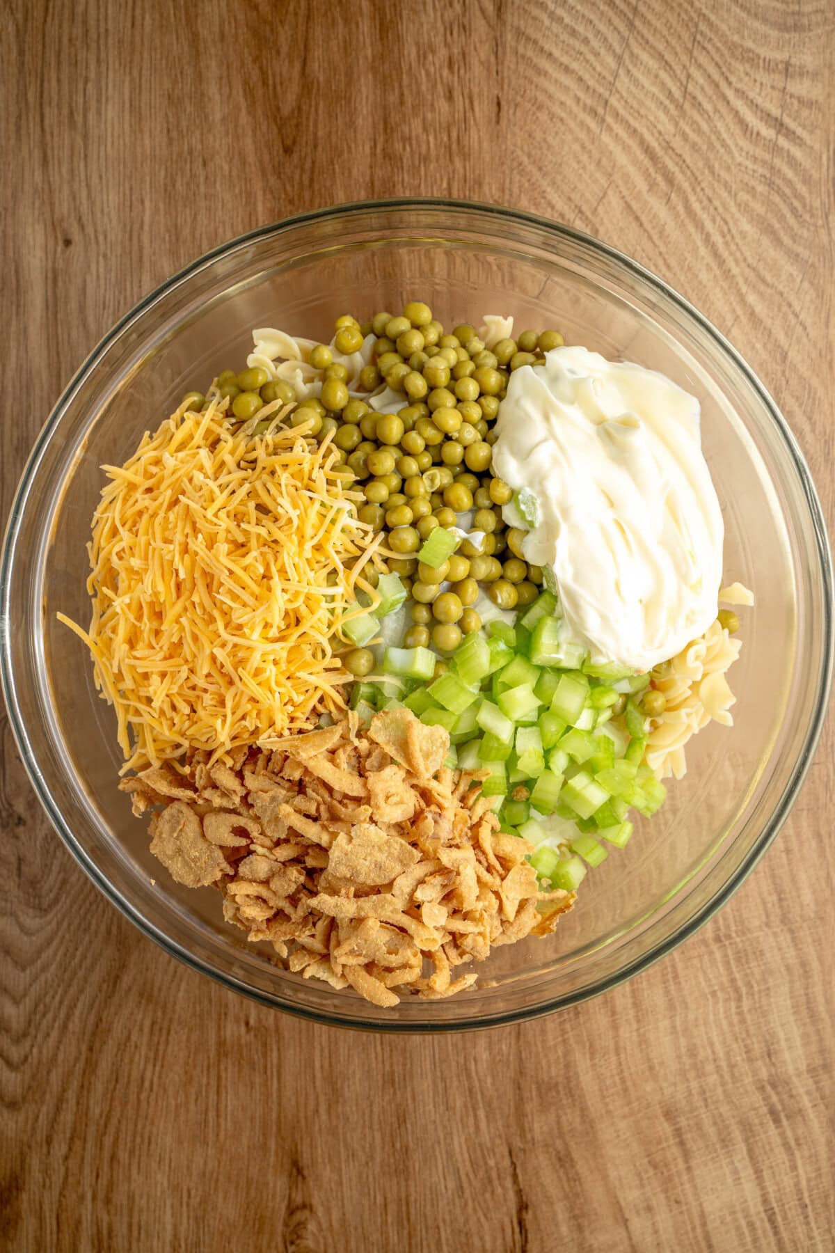 Cream of chicken soup, mayonnaise, milk, onion, celery, and tuna added to a glass mixing bowl.