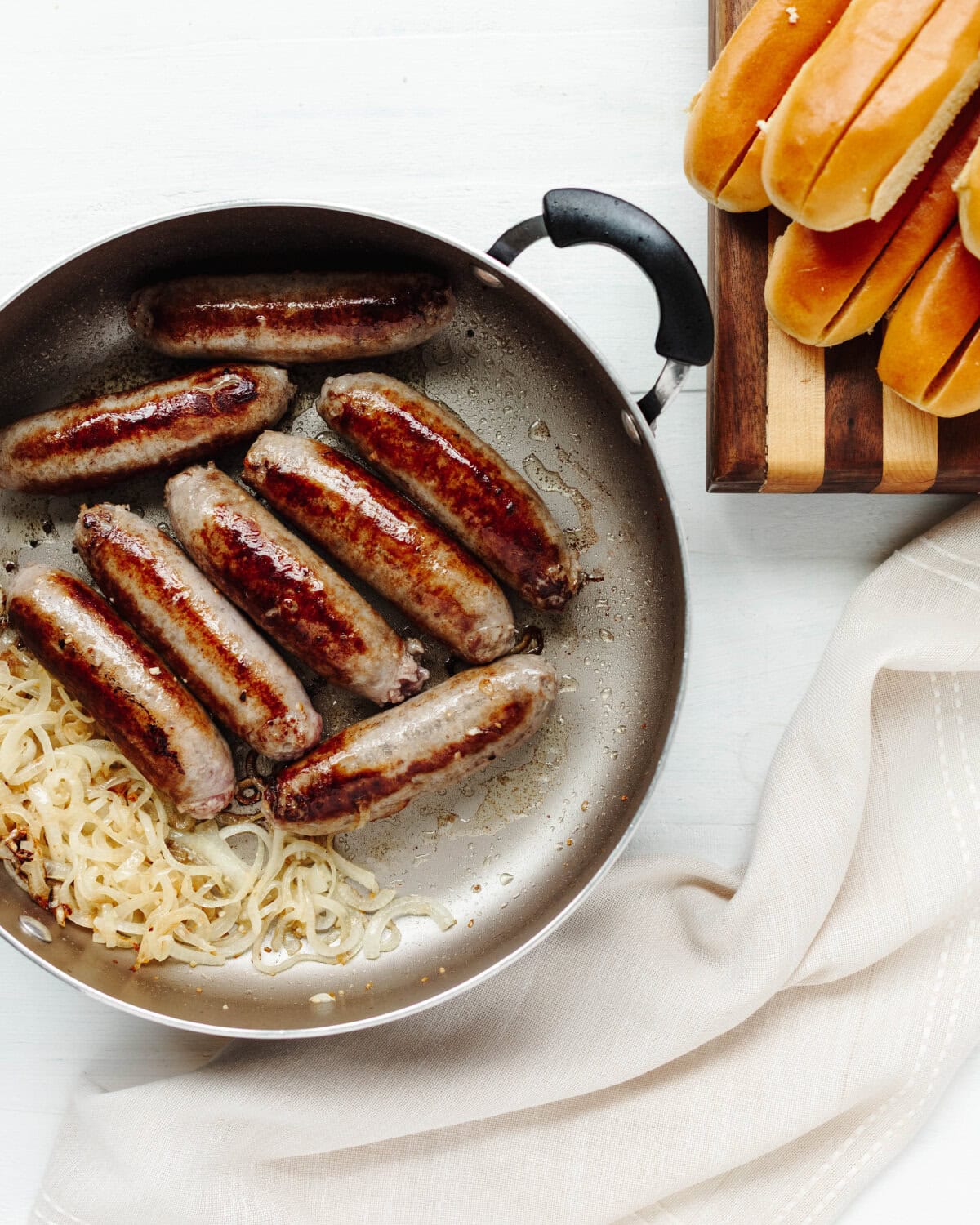Bratwursts cooking in a skillet until browned.