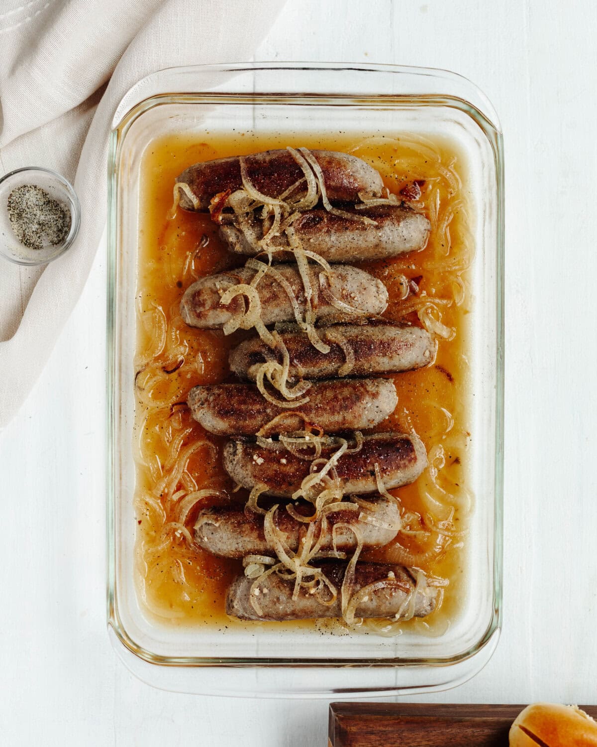Brats and onions transferred to a baking dish and cooked in a beer mixture.