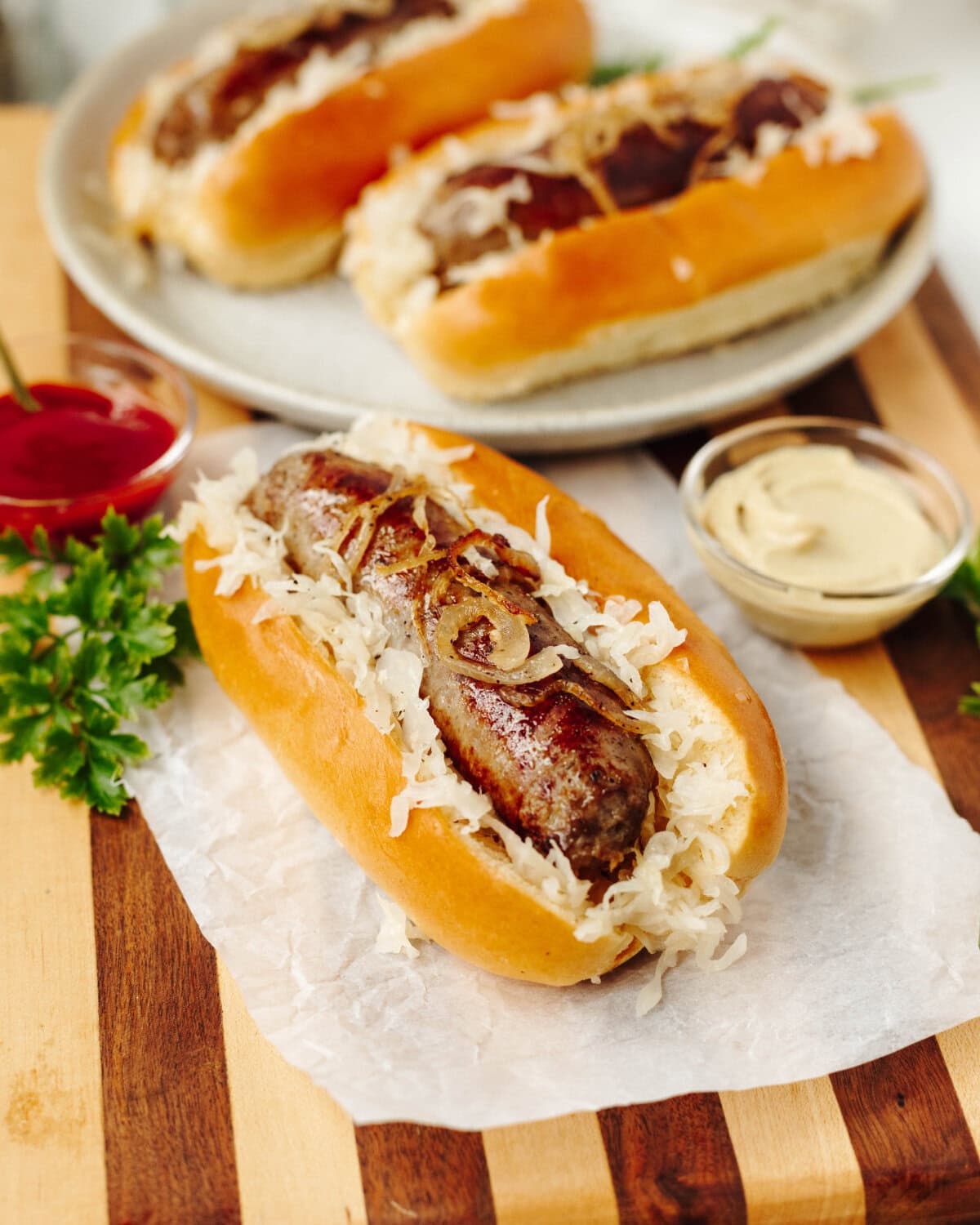 A bratwurst served in a bun with onions and seasonings and served on a wood cutting board.