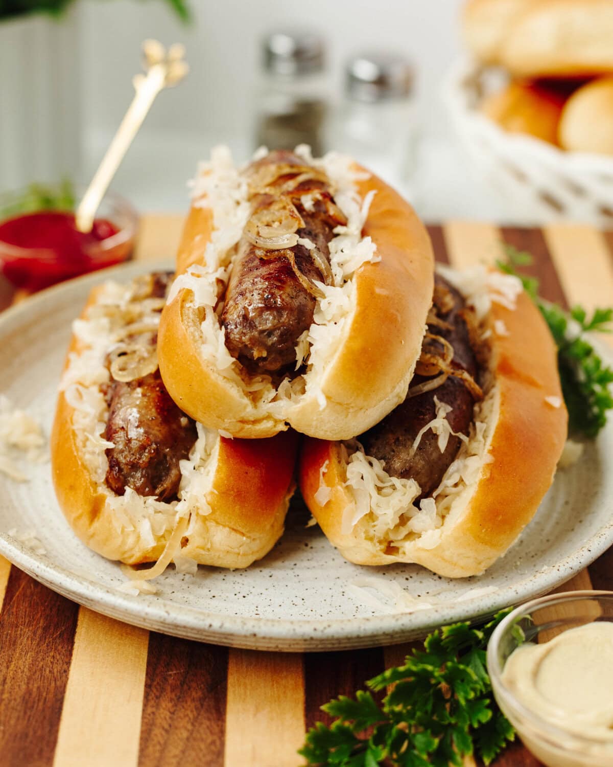 A stack of three sausage bratwursts served in a bun with onion and garlic.