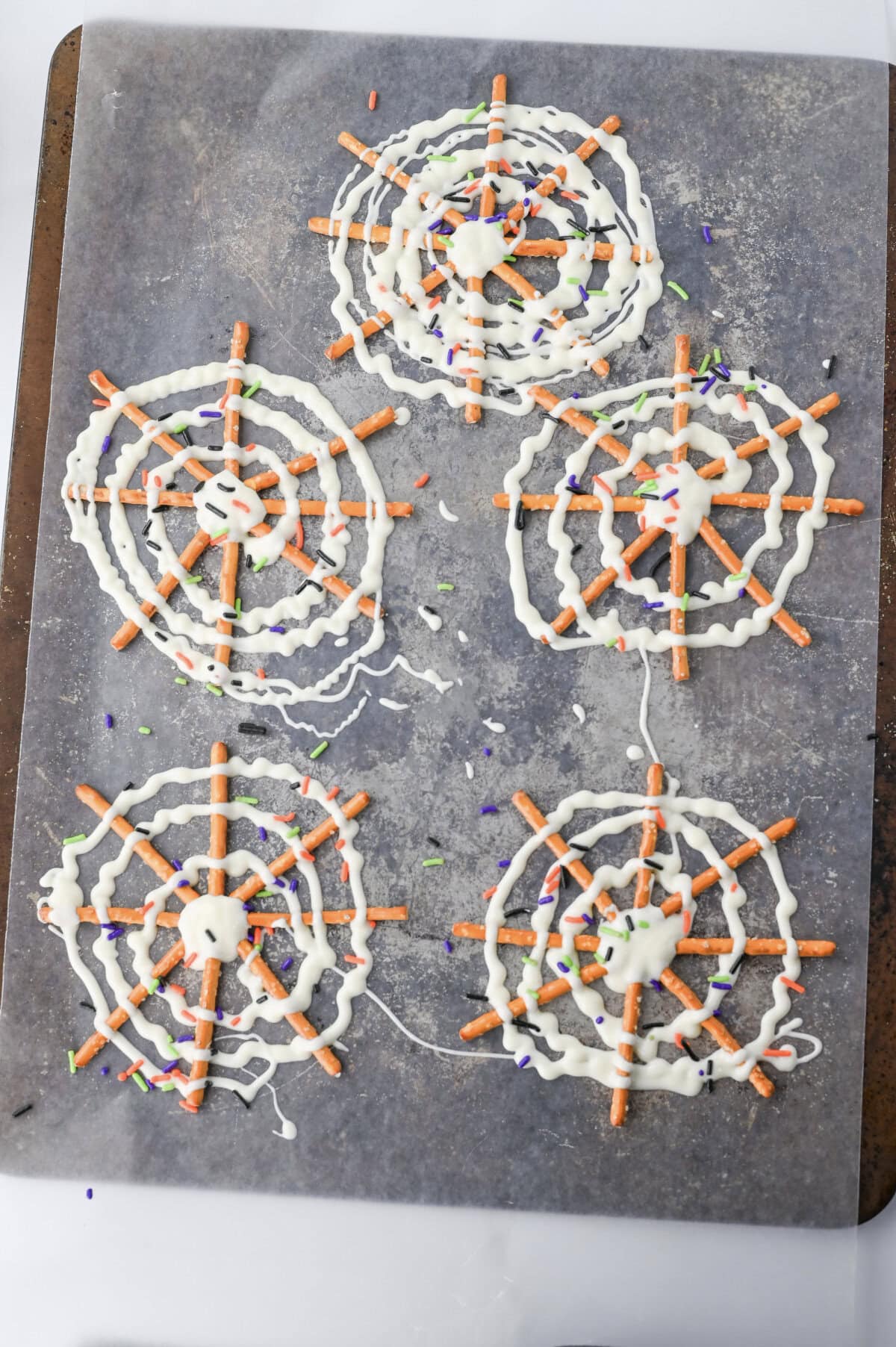 White melting chocolate drizzled around pretzel stacks to mimic spider webs.