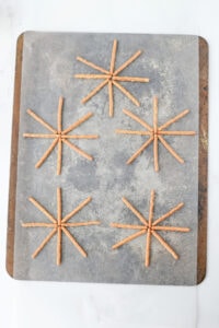 Pretzel sticks aligned into circles on a parchment lined cookie sheet.