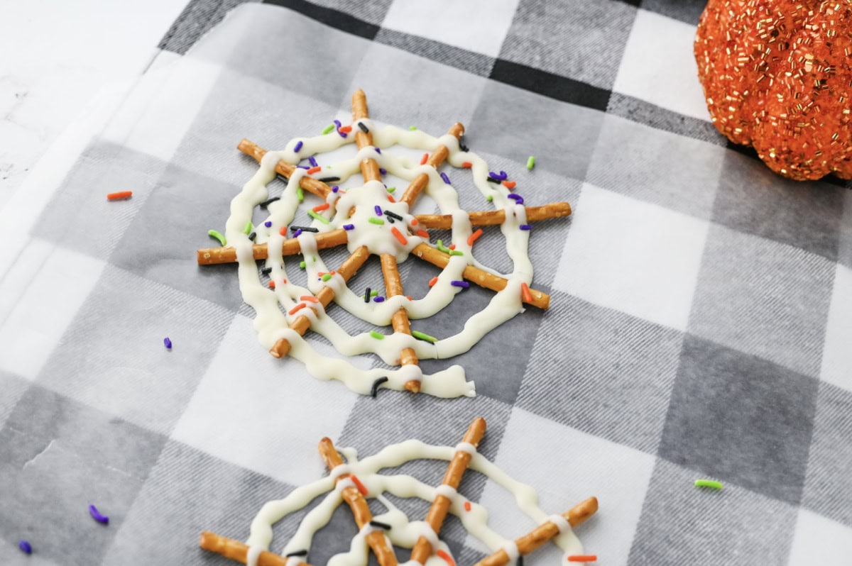 Spider web chocolate pretzels on a plaid napkin.