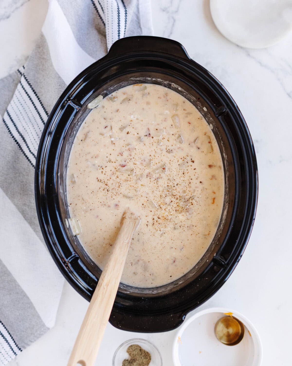 A creamy milk mixture poured into the potato mixture in a slow cooker liner.
